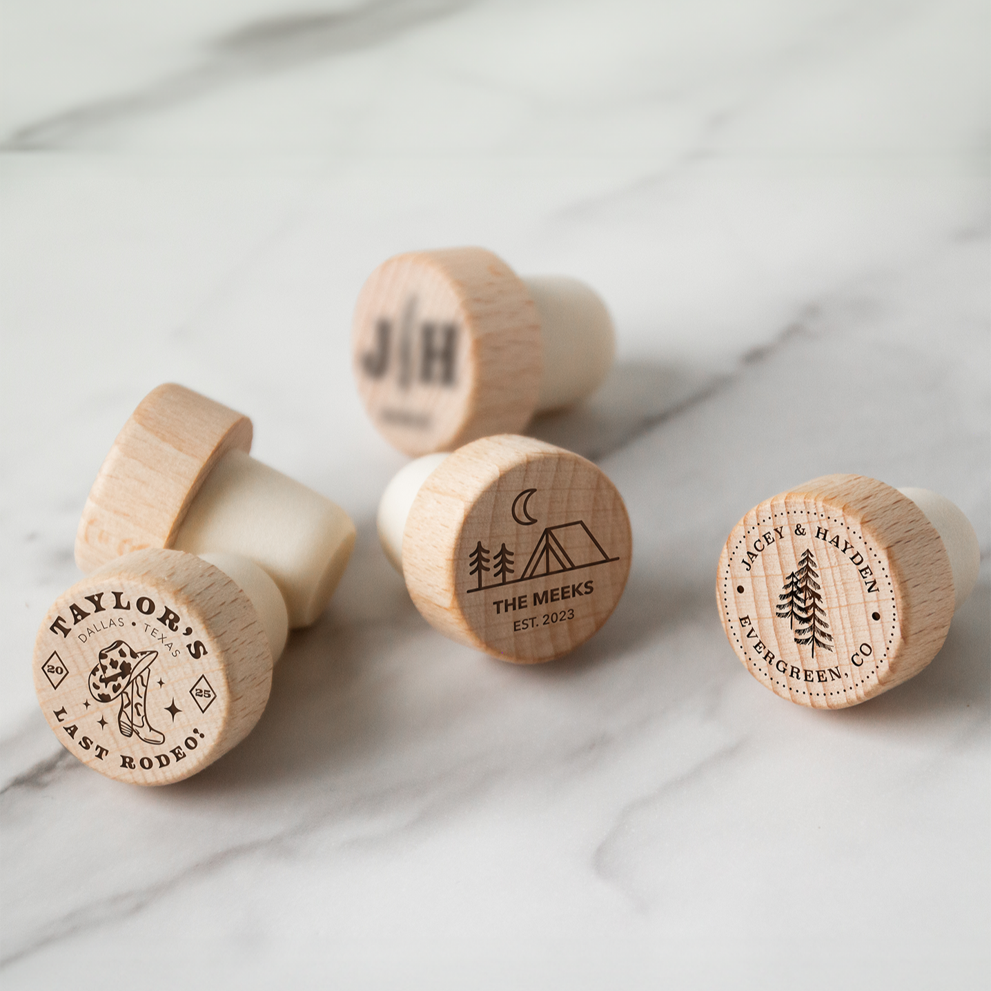 Set of wooden wine bottle stoppers with engraved designs on a marble surface